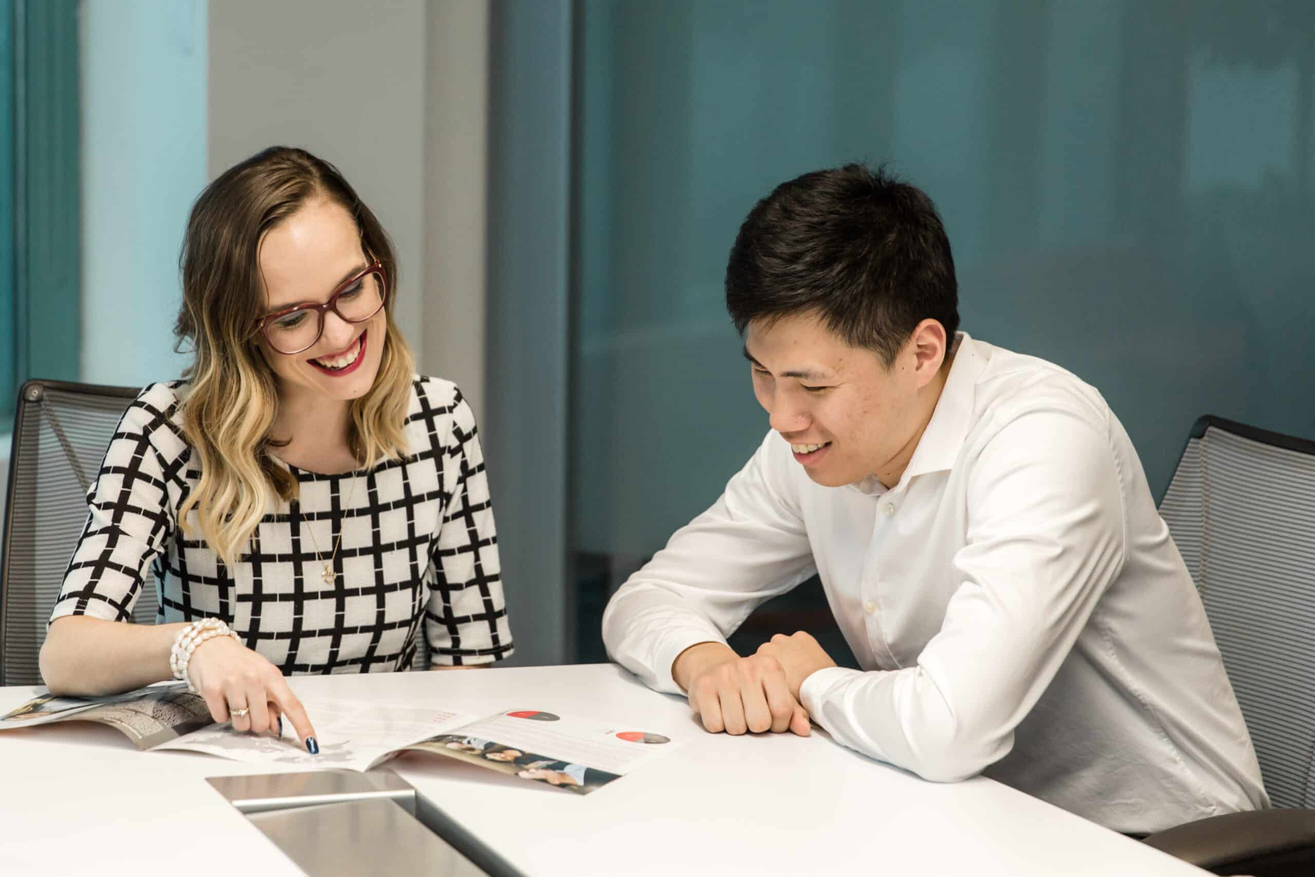 Woman pointing a section of a book to man while in a meeting