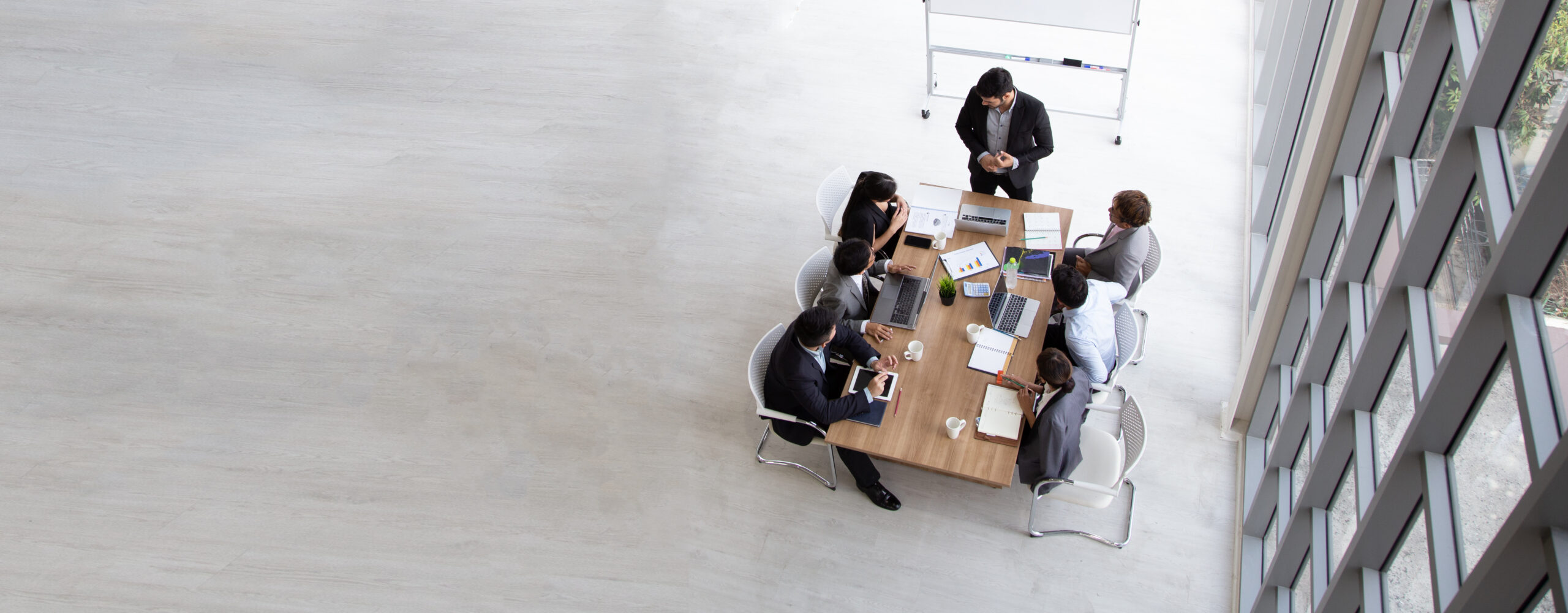 top view of group of multiethnic busy people working in an office, aerial view with businessman and businesswoman sitting around a conference table with blank copy space, business meeting concept