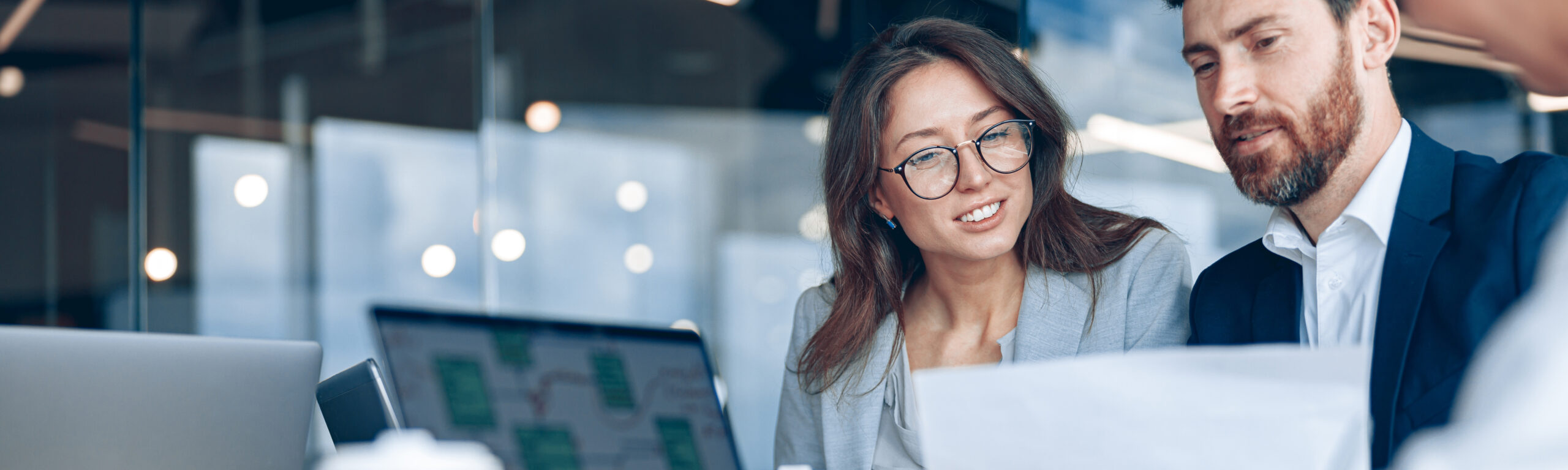 close up of smiling businessmen discussing documents with graphs and charts in a modern office