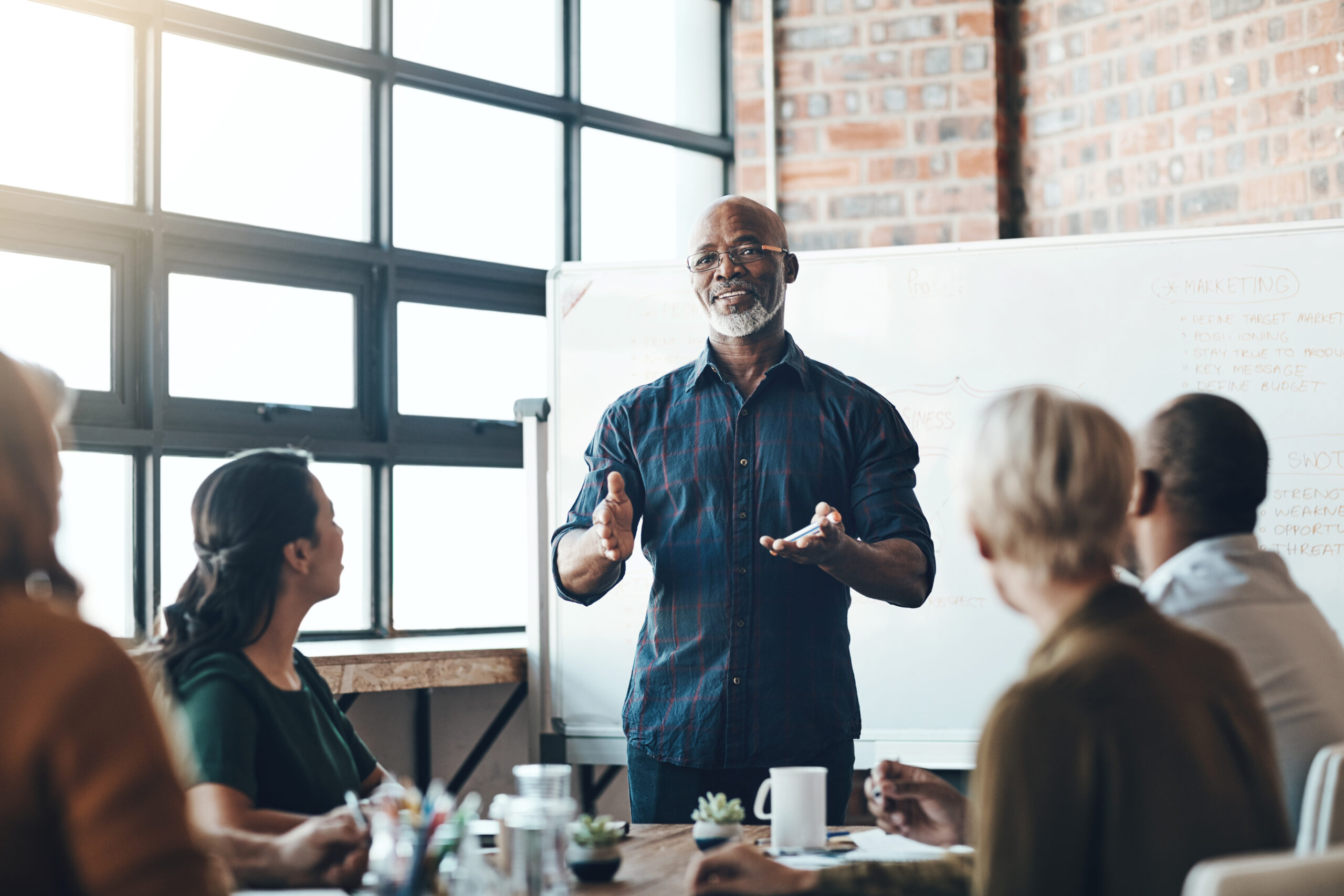 senior business man doing presentation, planning and talking in a meeting, seminar or training workshop in a boardroom. manager sharing ideas, teaching and coaching new employees during conference