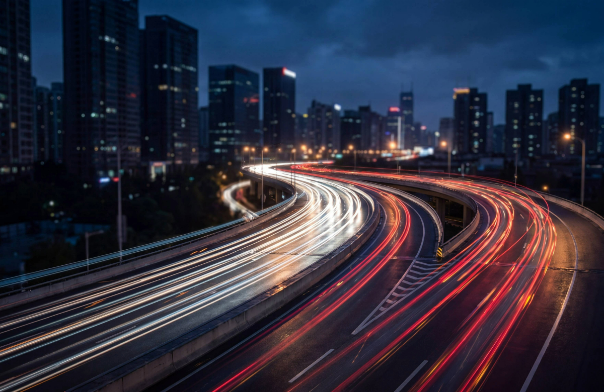 Nighttime cityscape with a curved elevated highway and long-exposure light trails from cars