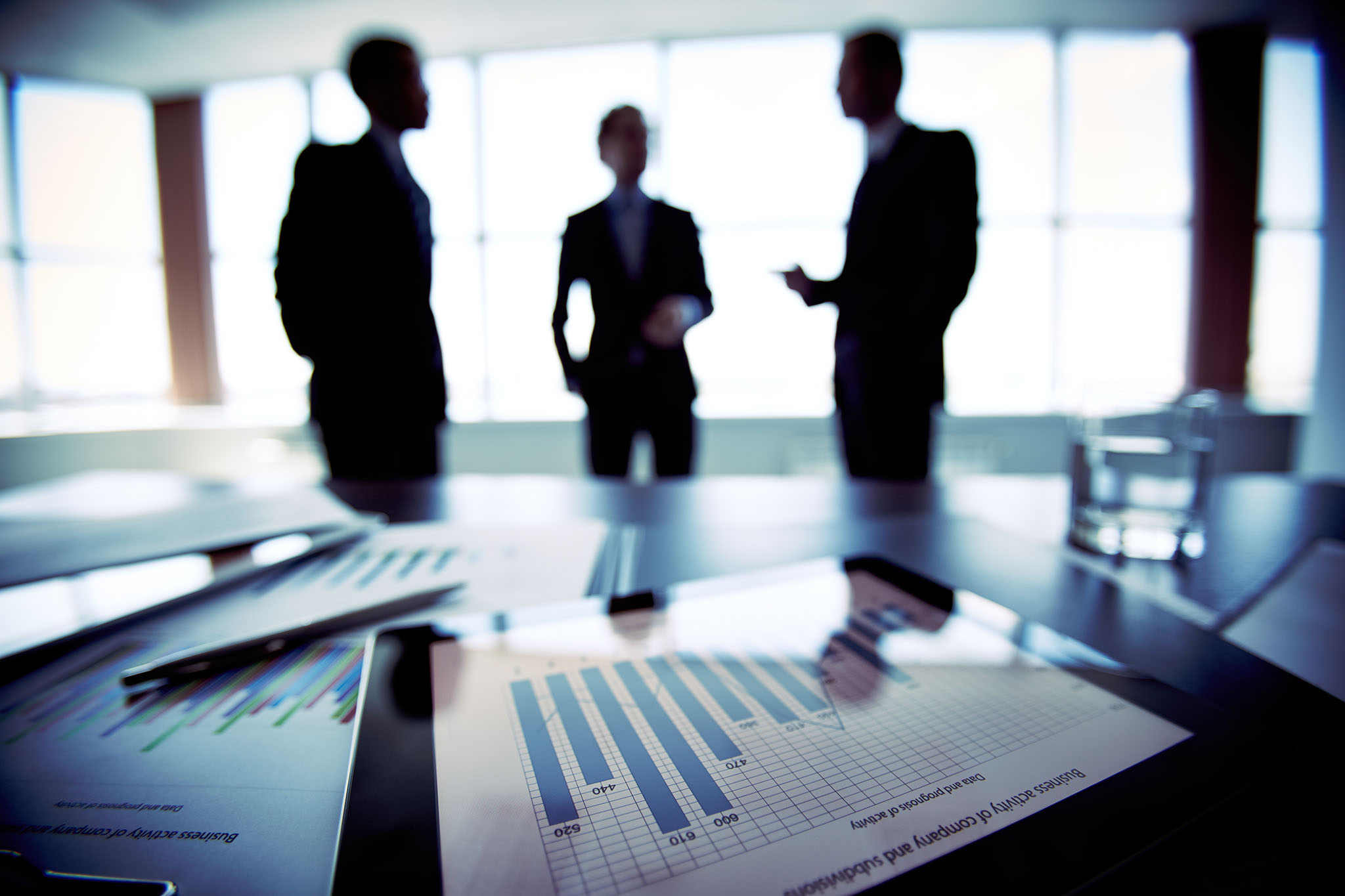 Three men discussing while looking at a graph of Business activity
